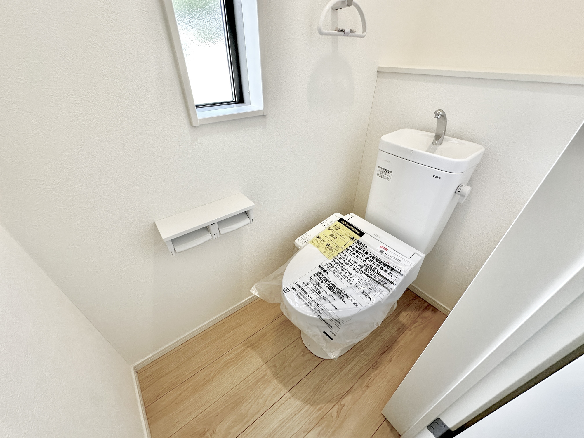 千曲市戸倉第６　新築住宅全５棟のトイレ|節水性能の高いトイレはもちろんウォシュレット付き♪便器のフチがないタイプなので、お掃除もサッとひと拭きでOK！壁埋込型収納も付いており、スッキリ広々とご利用いただけます。