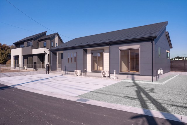 2号棟《完成イメージ》ダークグレーと木目調のツートンカラーが落ち着いた印象の平屋建て。大きな掃き出し窓から光が降り注ぐ明るいLDKと、洋室のスリット窓がデザインのアクセントの心地よい住まいです。