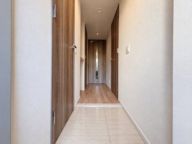 ワコーレ阿倍野播摩町ラフィリスの玄関|明るい色合いの床材とダークブラウンの建具が調和した、落ち着きのある玄関・廊下です。玄関から室内へと続