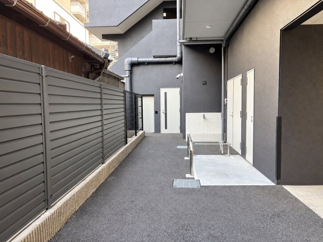 ワコーレ阿倍野播摩町ラフィリスのその他|ダークグレーの外壁と目隠しフェンスが印象的な共用スペースです。建物のデザインに統一感があり、落ち着い