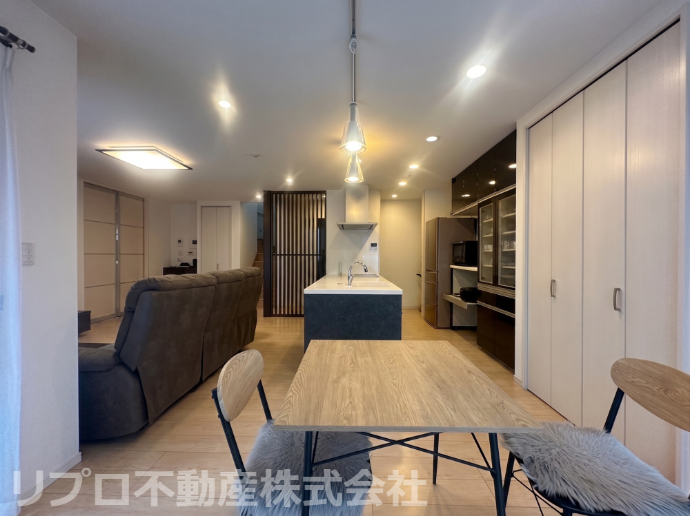 印西市東の原2丁目の居間・リビング|スタイリッシュなモダンデザインの広々LDK！開放感のあるオープンキッチンや縦格子が印象的で、豊富な収納も魅力です！※AI画像使用しています