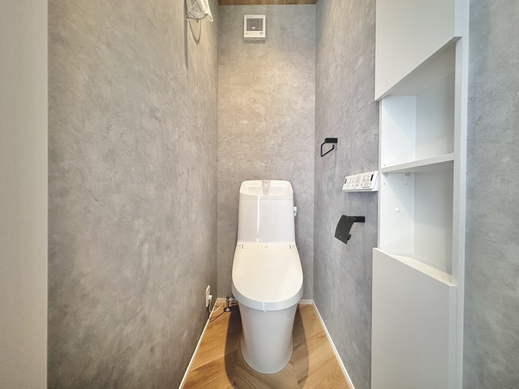 スタイリッシュなアクセントクロスと木目調フロアがおしゃれなトイレ空間！トイレットペーパーや掃除用品をスマートに収納できる埋め込み棚を完備♪掃除がしやすく清潔感を保てるため、毎日快適に使用できます！