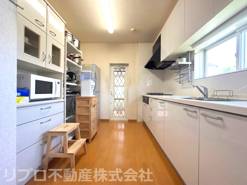 野田市清水戸建のキッチン|ゆとりの通路幅と勝手口付き、収納力豊かな明るいシステムキッチン！