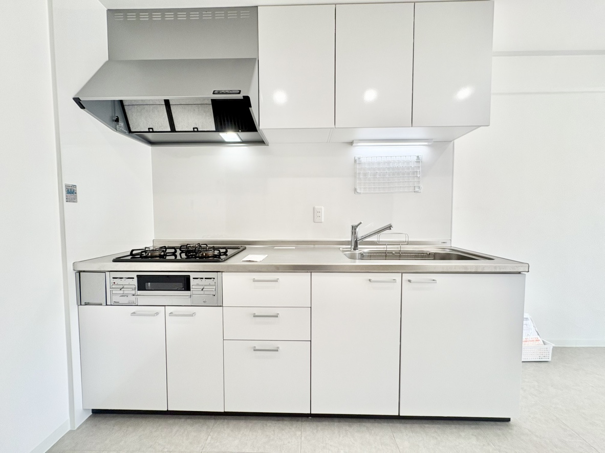 荒神山マンションのキッチン|白を基調とした清潔感あふれるシステムキッチン。壁面にすっきりと収まる配置のため、リビングスペースを無駄なく広く使えます。上下に豊富な収納スペースを備え、調理器具や食器もすっきりと綺麗に片付きます