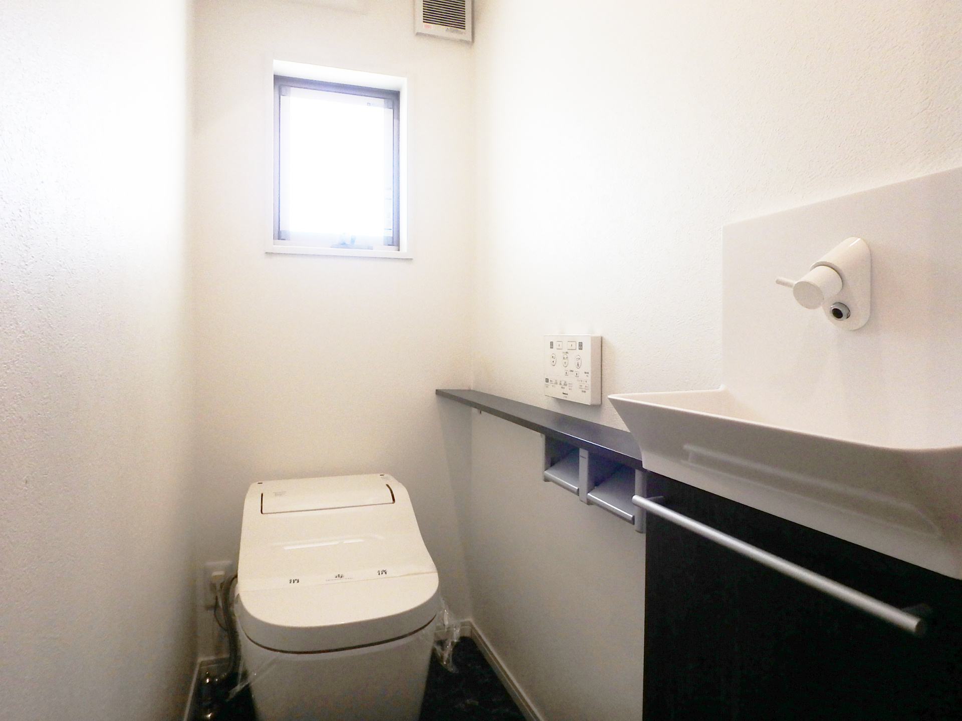 西難波町五丁目戸建のトイレ|1階トイレは便座の横にお手洗いが付いています。上部に窓、タンクレスの便器のため、明るくスタイリッシュなトイレです。