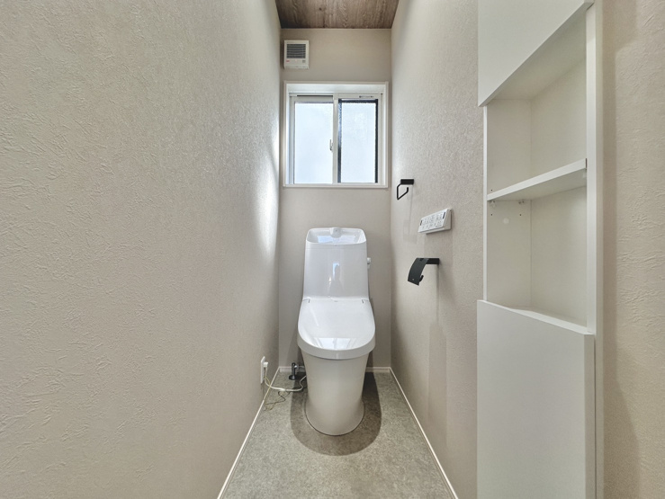 木目調天井と壁面埋め込み棚がおしゃれな清潔感漂うトイレ空間！備え付けの収納棚には予備のトイレットペーパーや掃除用品をスマートに収納でき、小窓からの換気もスムーズで日常を快適に過ごせます♪