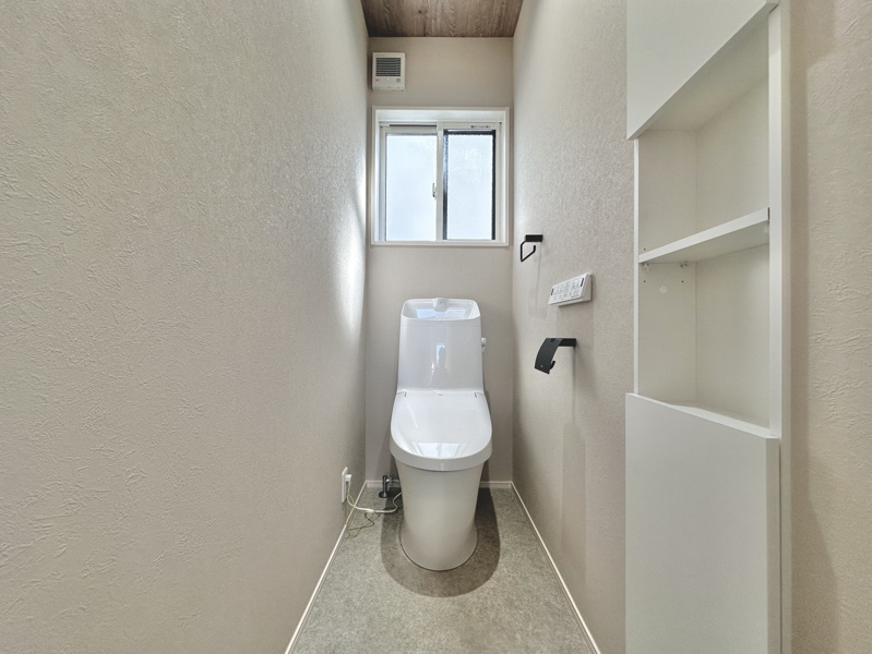 木目調天井と壁面埋め込み棚がおしゃれな清潔感漂うトイレ空間！備え付けの収納棚には予備のトイレットペーパーや掃除用品をスマートに収納でき、小窓からの換気もスムーズで日常を快適に過ごせます♪