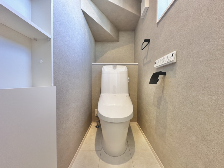 清潔感あふれる温水洗浄便座付きのトイレスペース！階段下の空間を賢く活用し、予備のトイレットペーパーや清掃用品をサッと置ける棚を設置♪お掃除もしやすいスリムなデザインで快適に利用できますね！